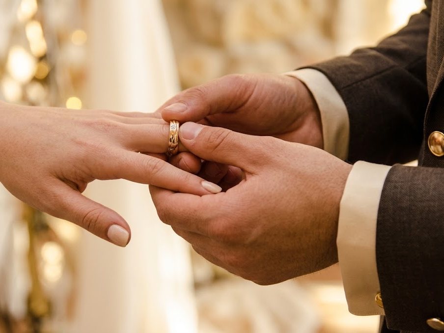 A groom placing a wedding ring on his bride's finger